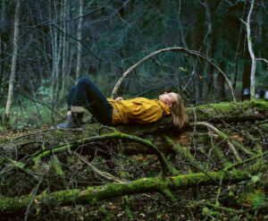 Nainen lepää kaatuneen puun rungolla metsässä